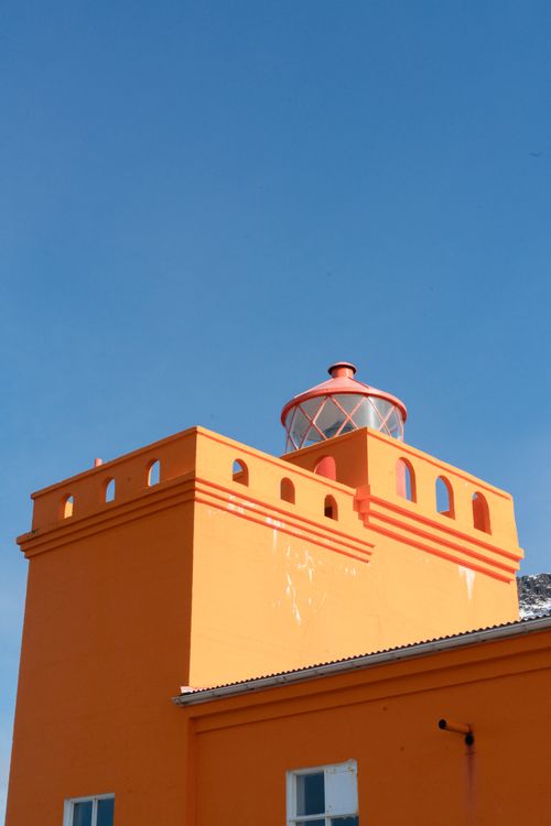 Vibrant Orange Lighthouse Against Blue Sky · Free Stock Photo