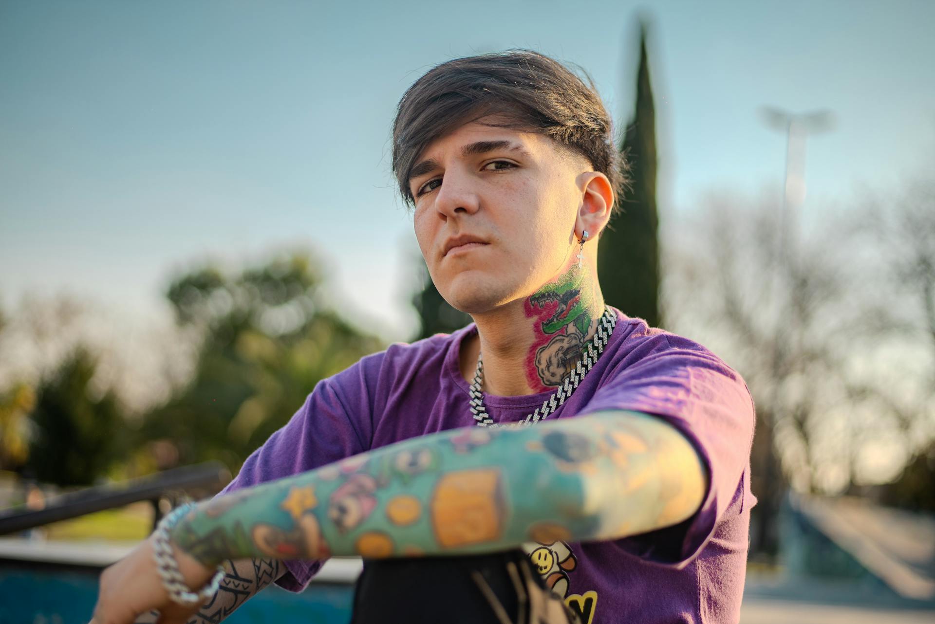 Portrait of a young tattooed man with vibrant ink outdoors, exuding fashion and style.