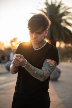 Person with tattoos standing outdoors at sunset, creating a moody atmosphere.