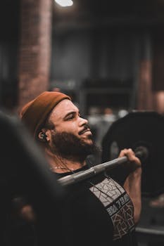 A determined man lifting weights in a gym, showcasing strength and concentration.