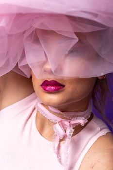 Close-up portrait of a woman with pink tulle, highlighting vibrant lips and fashion style.