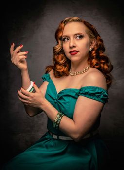 Vintage styled woman in green dress applying makeup in classic portrait.