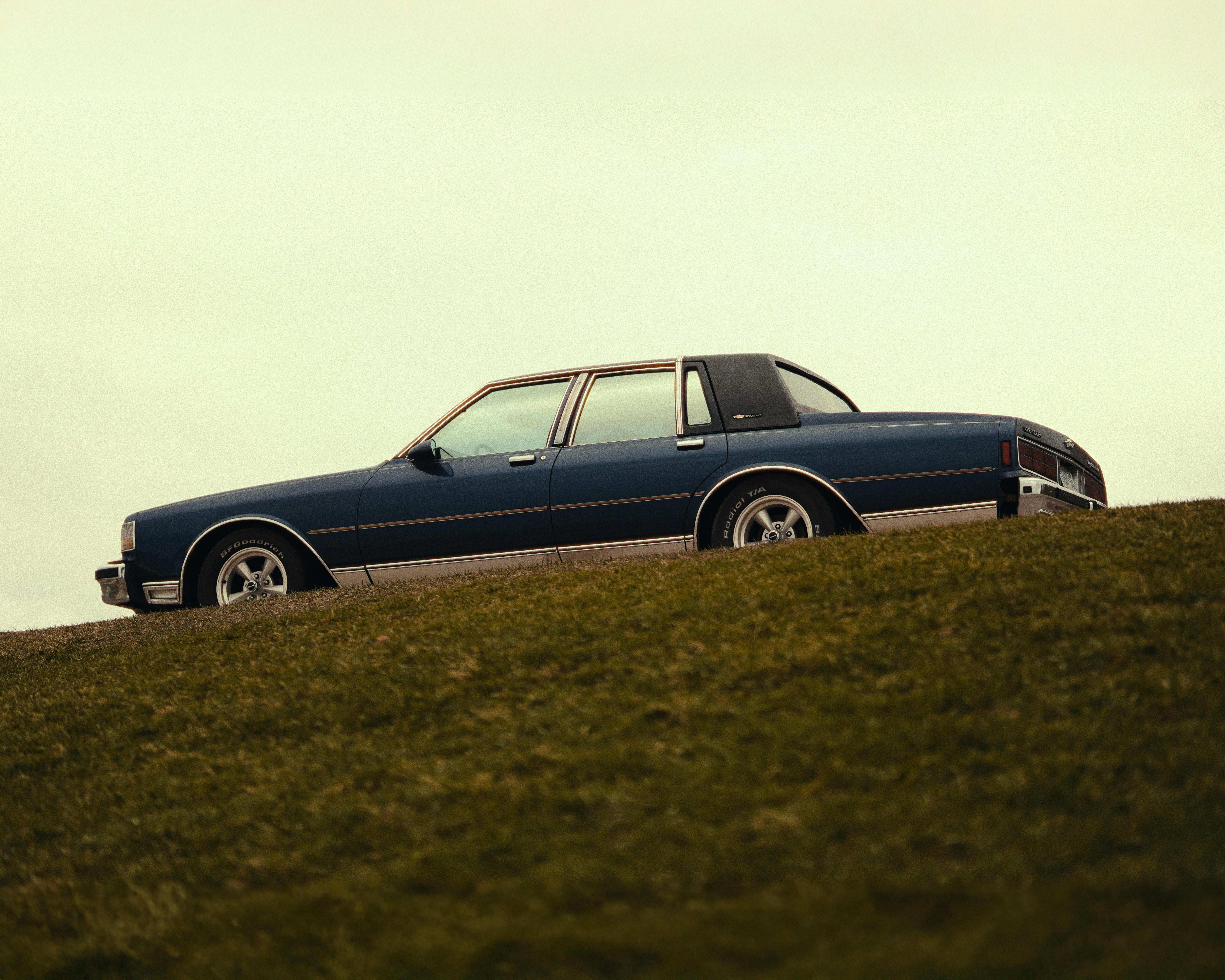 Classic 1980s Chevrolet car parked on a grassy hill, showcasing vintage automotive style.