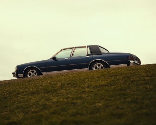 Free Classic 1980s Chevrolet car parked on a grassy hill, showcasing vintage automotive style. Stock Photo