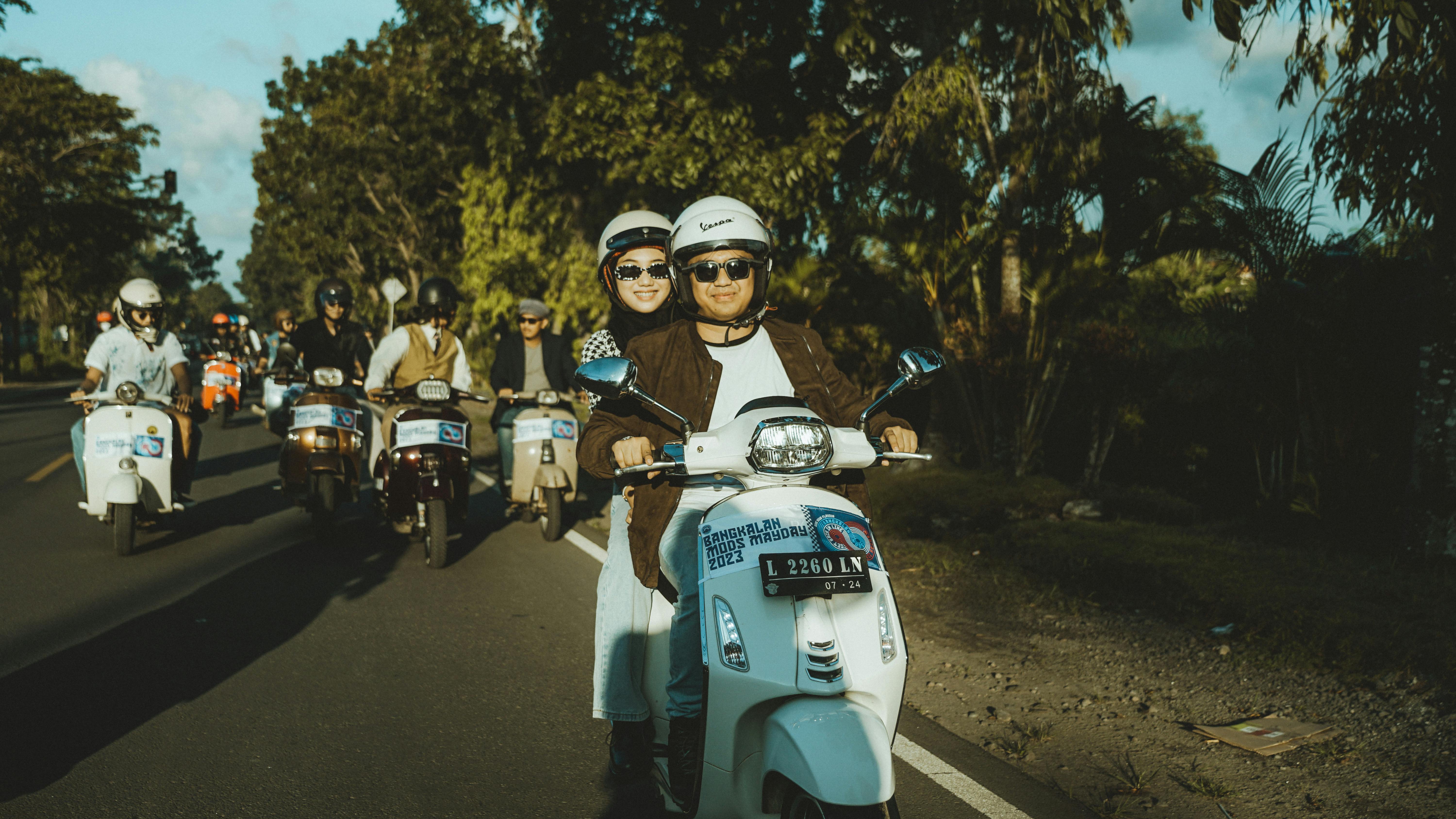 ingyenes Egy örömteli pár Vespa robogón ül egy csoporttal a festői Kelet-Jáván, Indonéziában. Stockfotó