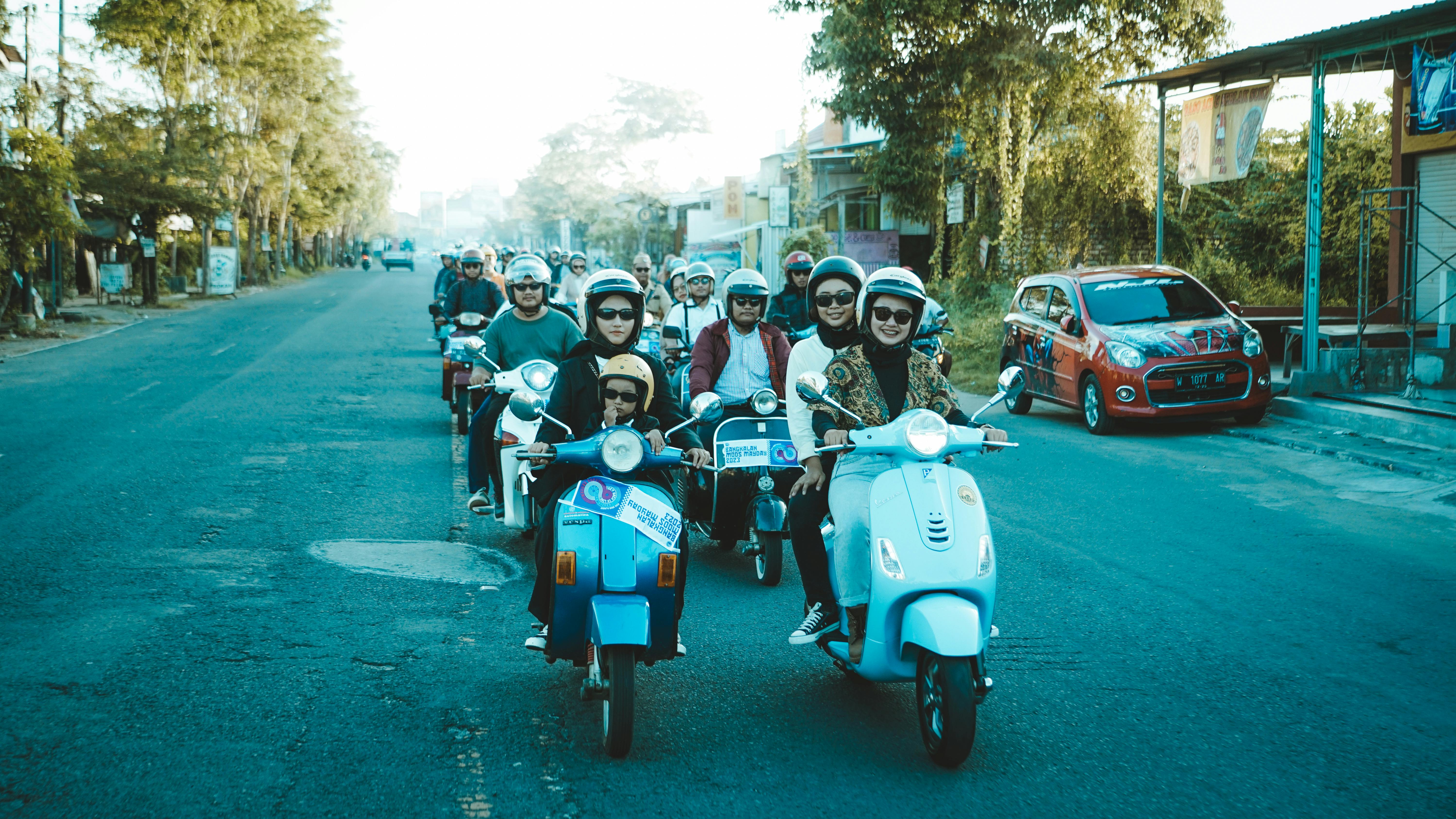 Gratis Sekelompok orang dewasa yang ceria mengendarai skuter di jalan di Jawa Timur, Indonesia. Foto Stok