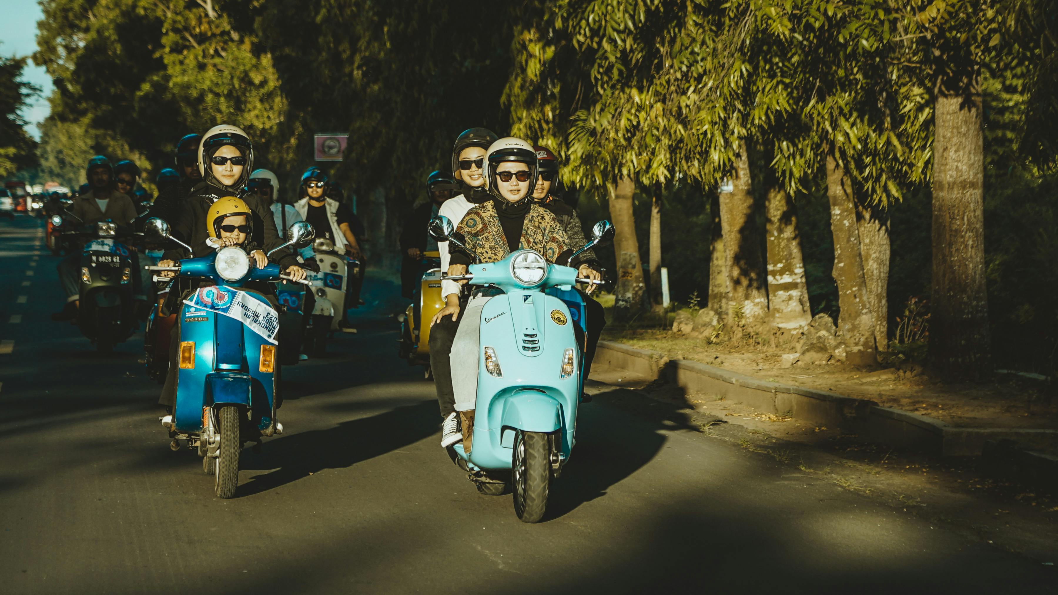 免费 一群成年人骑着 Vespa 摩托车穿越阳光明媚的印度尼西亚东爪哇。 素材图片