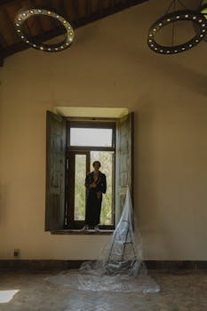 A person standing in an elegant room by an open window with rustic decor.