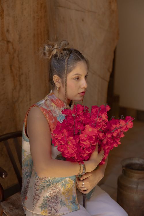Free A thoughtful young woman holds a bouquet of bright pink flowers indoors. Stock Photo