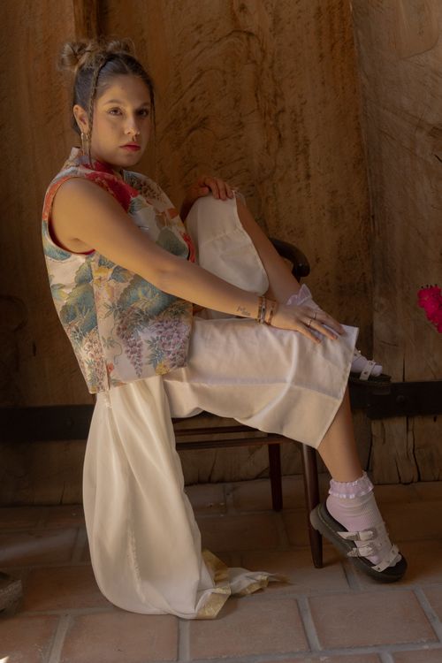 Free Young woman in modern fashion sitting indoors with a contemplative expression. Stock Photo