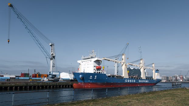 A cargo ship alongside towering cranes at Hamburg Port, showcasing global trade.