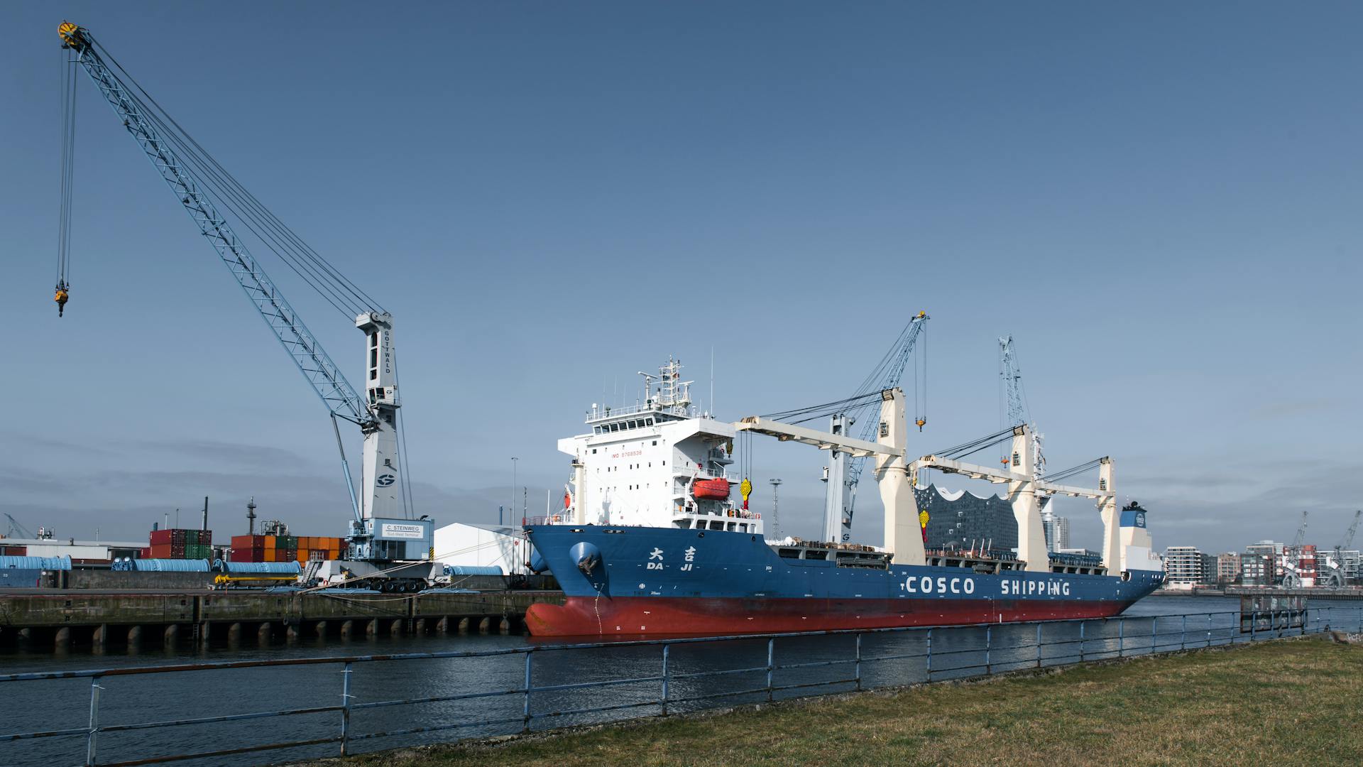 A cargo ship alongside towering cranes at Hamburg Port, showcasing global trade.