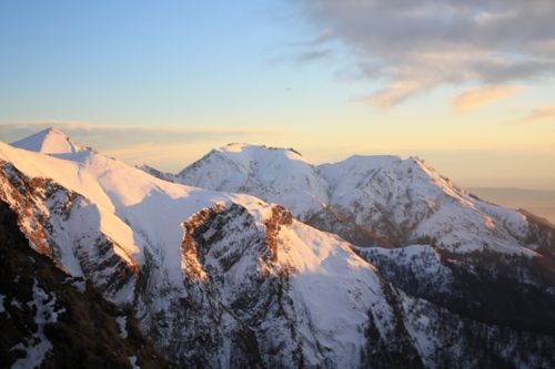 Free Snow-covered mountain peaks illuminated by the warm glow of sunset. Stock Photo