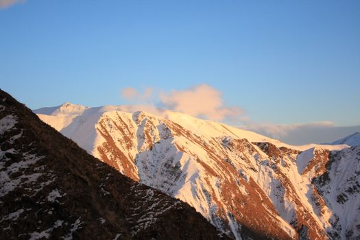 Breathtaking view of a snow-capped mountain range bathed in warm sunrise light.