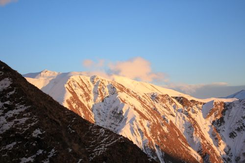 Free Breathtaking view of a snow-capped mountain range bathed in warm sunrise light. Stock Photo