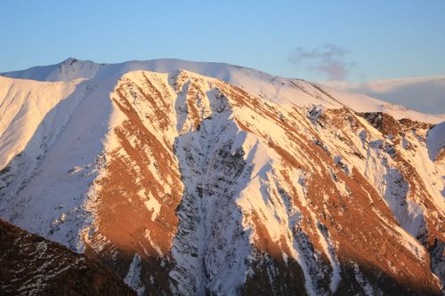 Free Stunning snow-covered mountain peaks illuminated by the warm hues of sunrise. Stock Photo