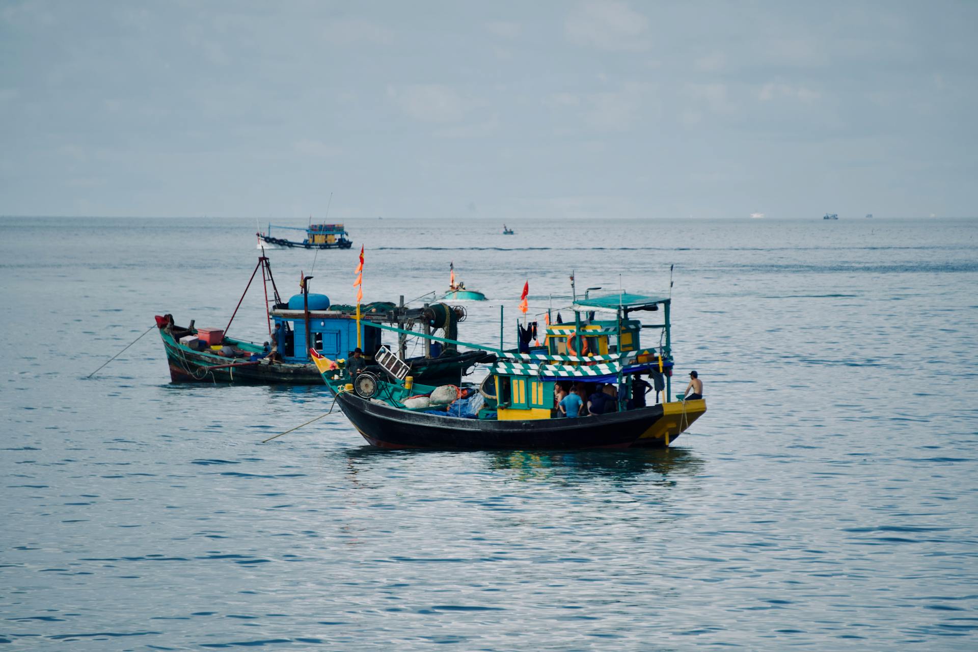 Vibrant fishing boats float on a tranquil sea under a cloudy sky, evoking a sense of peacefulness.