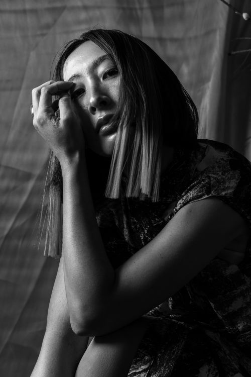 Free Black and white artistic portrait of a woman in a contemplative pose capturing emotion and texture. Stock Photo
