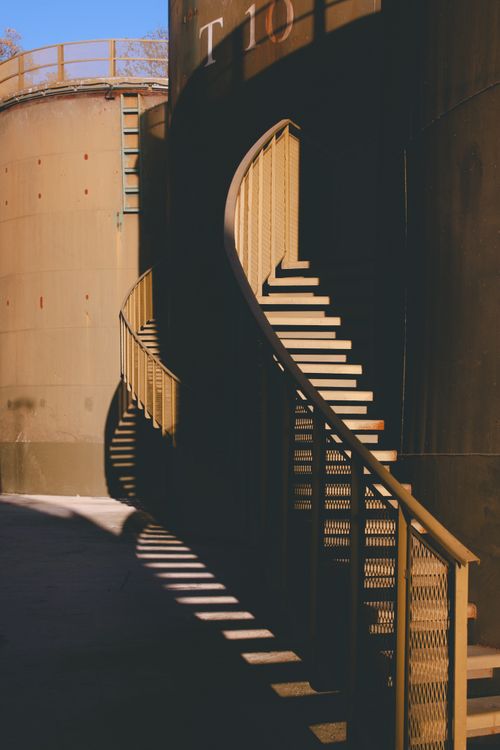 Free Elegant spiral staircase casting intricate shadows in an industrial exterior setting. Stock Photo