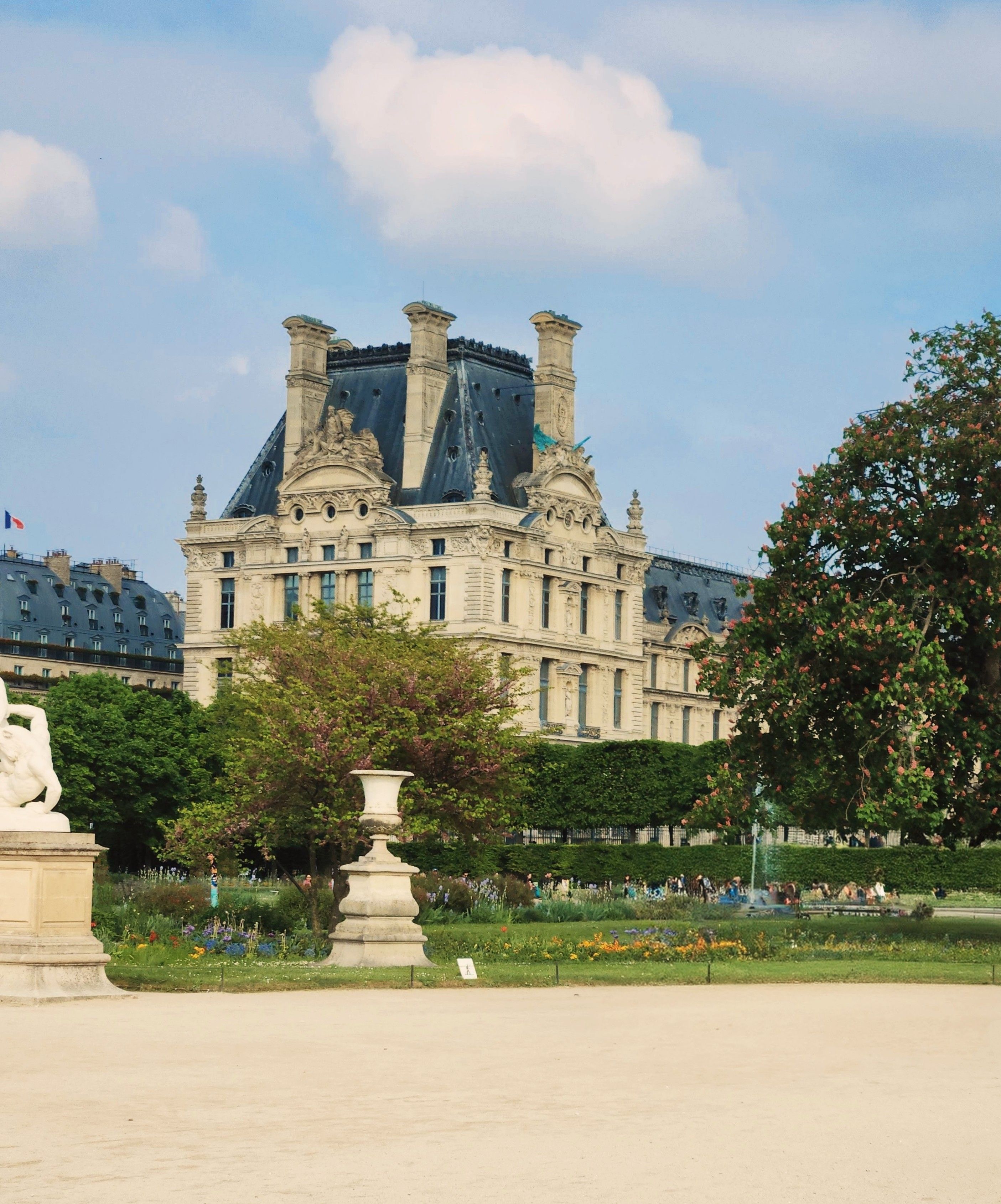 A picturesque view of the Louvre Palace with lush gardens in Paris, France.