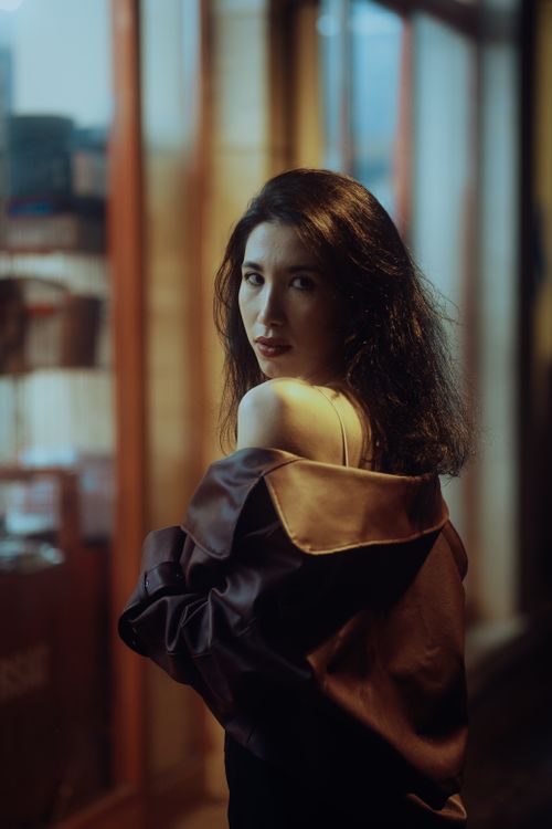 Free Woman in a fashionable coat looking over shoulder in urban night scene. Stock Photo