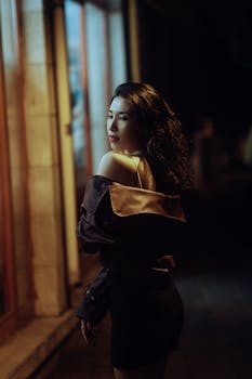 Stylish woman posing confidently in urban night scene with dim lights.