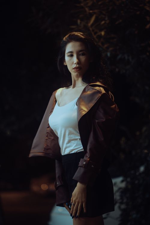 Free Elegant woman poses in stylish outfit under soft night lighting, exuding fashion and mystery. Stock Photo