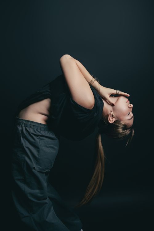 Free A woman performing a graceful yoga pose in low light, showcasing flexibility and elegance. Stock Photo