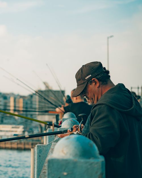 Free Men fishing from a bridge, urban setting, showcasing casual outdoor leisure activity. Stock Photo