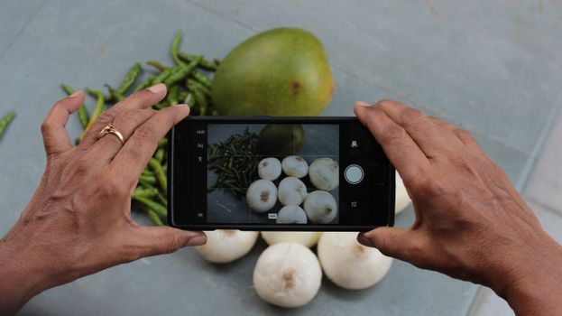 Capture of fresh mango, green chili, and onions through a mobile camera.