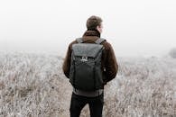 Man Standing on Field Carrying a Backpack