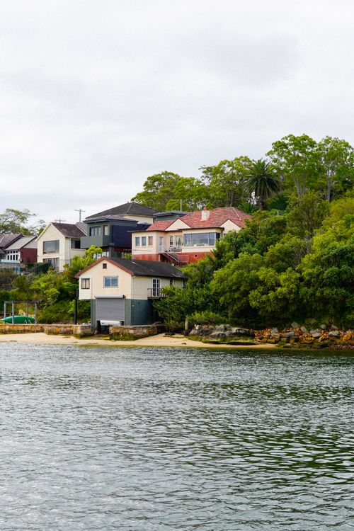 Free Picturesque coastal homes with lush greenery by a calm sea, showcasing serene seaside architecture. Stock Photo