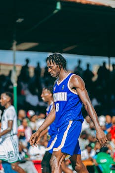 Tall male athlete in blue jersey during an outdoor basketball game.