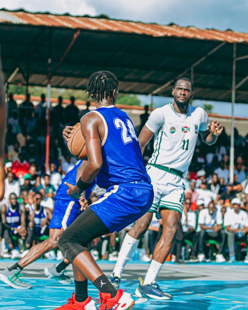 Free Outdoor basketball game with players in motion, surrounded by enthusiastic crowd. Stock Photo