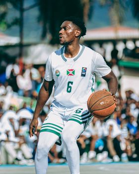 Focused athlete dribbling basketball on an outdoor court during a game.
