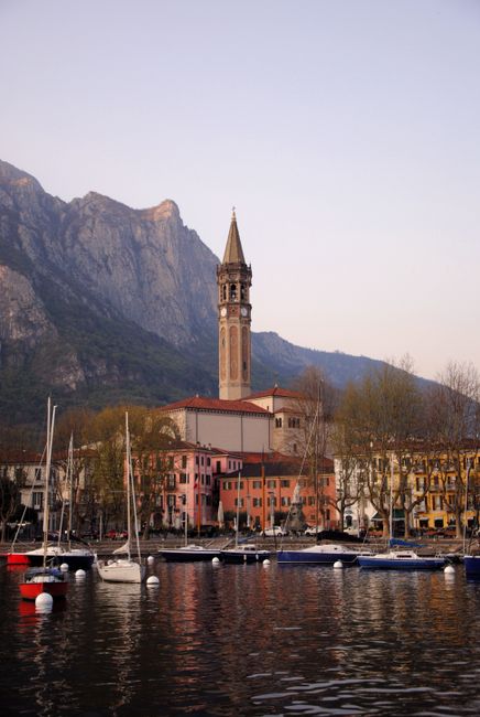 Beautiful Lecco town in Lombardy with colorful buildings, a bell tower, and mountains by the lake.