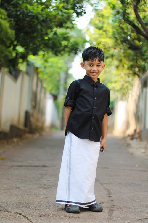 Free A cheerful young boy wearing traditional Kerala dress, captured outdoors with a vibrant, natural background. Stock Photo