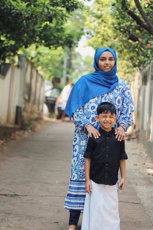 Free A mother and her son stand happily outdoors wearing traditional Kerala attire, showcasing cultural heritage. Stock Photo