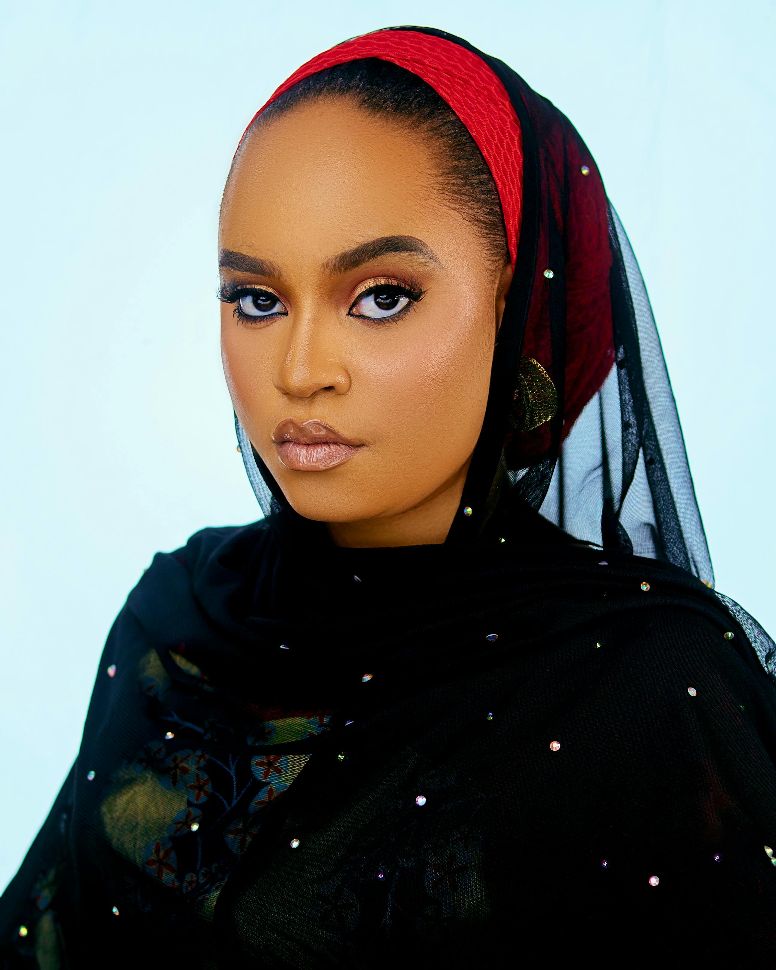 Portrait of a woman wearing a black traditional veil with a red headband showcasing elegance and poise.