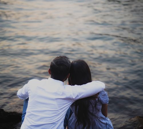 Free A couple enjoying a serene moment by the lakeside during sunset in Pune, India. Stock Photo