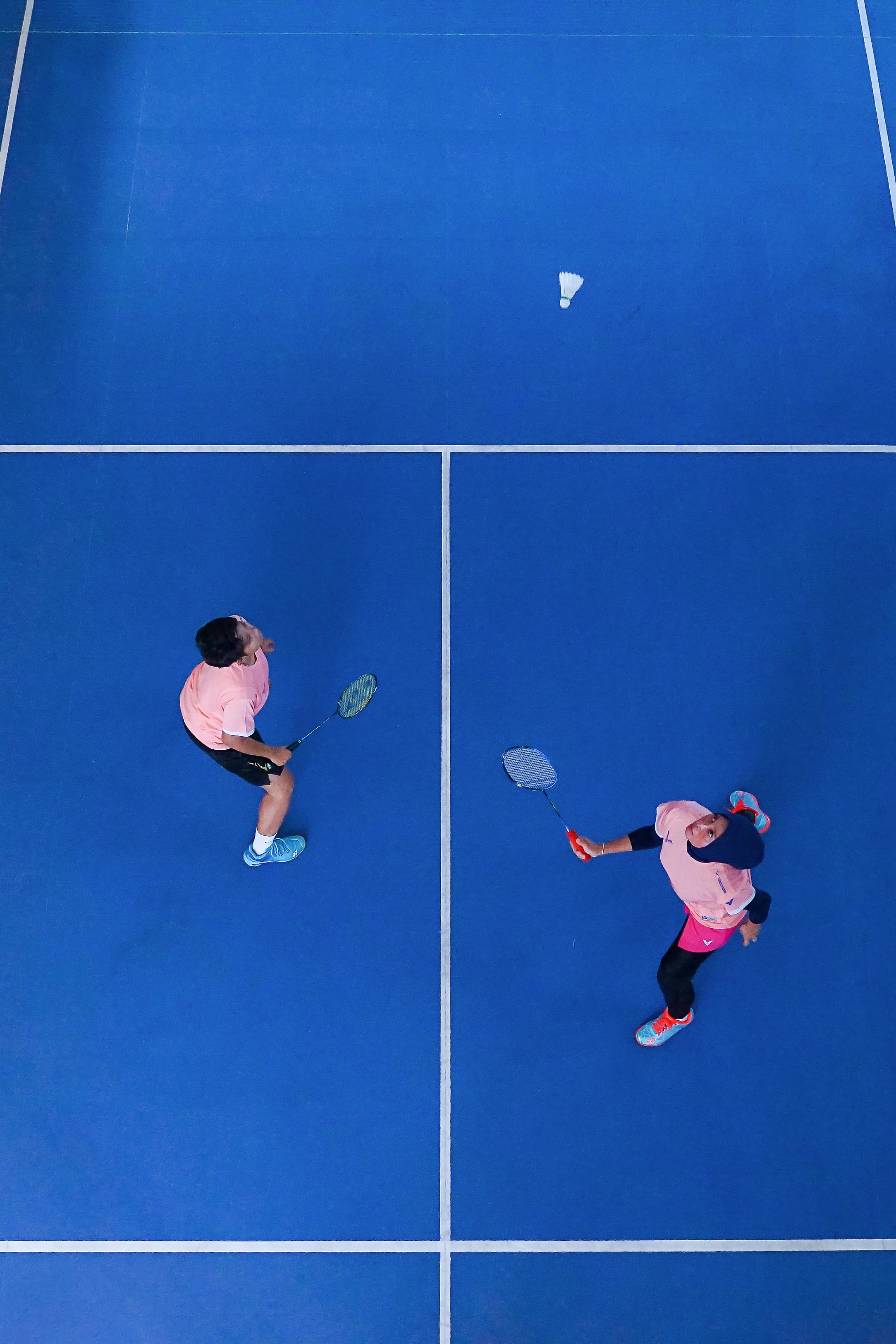 Aerial shot of two badminton players on a blue court in Jakarta, Indonesia.
