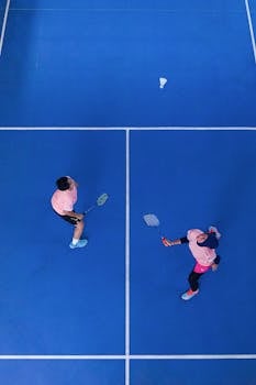 Aerial shot of two badminton players on a blue court in Jakarta, Indonesia.