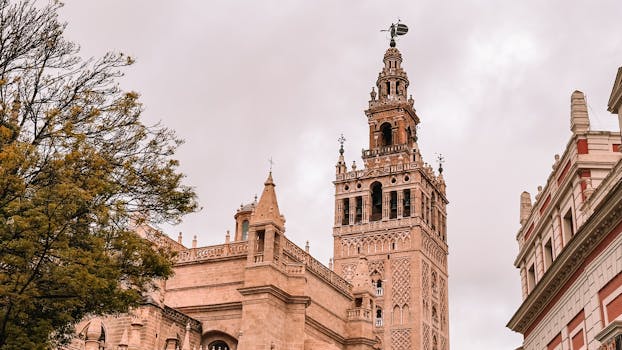 A striking view of the Giralda Tower against a cloudy sky in Sevilla, Spain.
