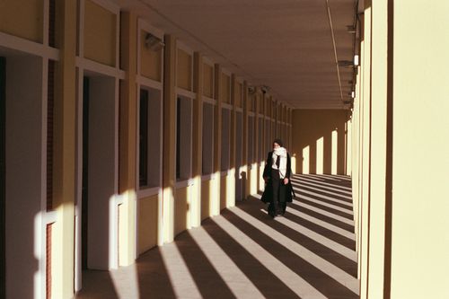 Free A woman walks through a sunlit corridor casting artistic shadows in Eskişehir, Türkiye. Stock Photo
