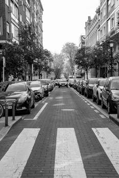 Black and white photo of a Madrid street with parked cars on both sides.