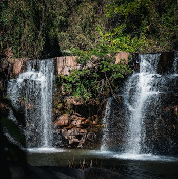 Stunning view of cascading waterfall amidst vibrant greenery in Thailand.