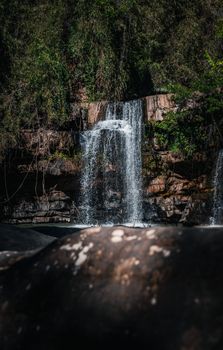 Tranquil waterfall in a lush Thai forest with cascading waters and vibrant greenery.
