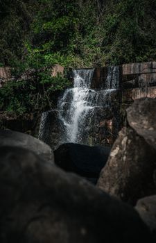 Tranquil waterfall cascading in a lush forest setting in Thailand.