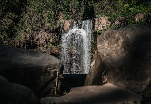 Scenic view of a cascading waterfall surrounded by lush greenery in Thailand.