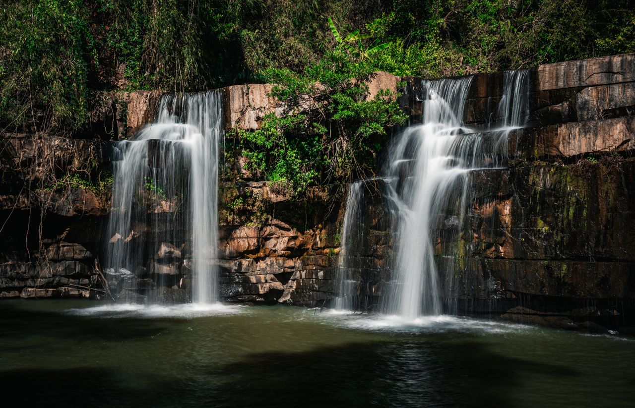 a stunning cascading waterfall surrounded by lush greenery in thailand